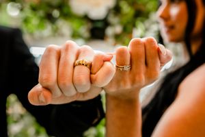 Close-up of hands showing wedding rings during ceremony.