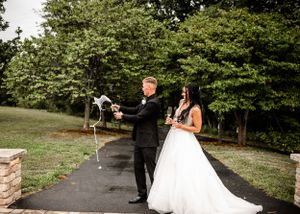 A couple poses for wedding photos in a garden setting with lush greenery.