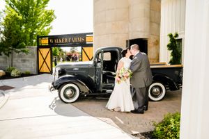 Classic vintage wedding cars parked outside elegant stone building for formal event.