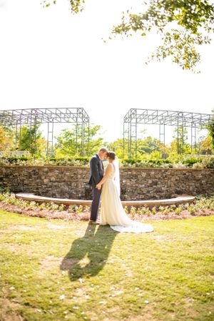 Wedding couple poses near stone wall with industrial backdrop.
