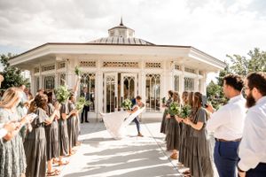 Wedding ceremony exit with guests lining pathway at elegant white venue.