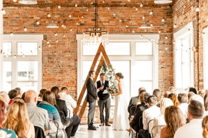 Wedding reception in rustic brick venue with string lights and wooden decor.