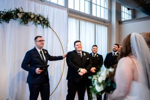 Wedding ceremony moments captured in a bright, modern venue with white draping.