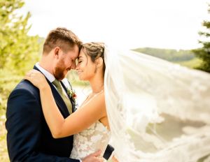 Sunlit wedding portraits with flowing veil creating ethereal romantic atmosphere.