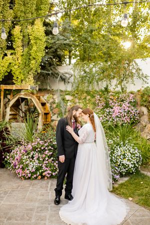 Garden wedding ceremony setting with blooming flowers and stone pathway.