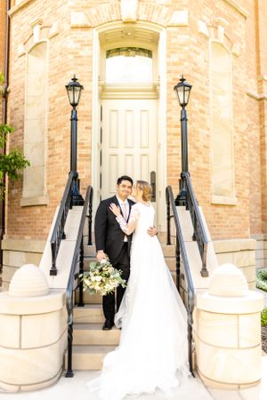Panoramic view of a brick church entrance with elegant white doors and black lamp posts.
