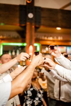 Guests raise shot glasses in a celebratory toast during wedding reception.