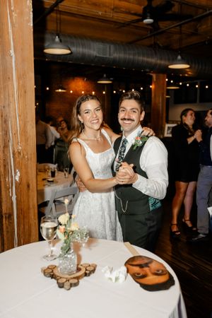 Wedding reception scene in rustic venue with wooden beams and warm lighting.
