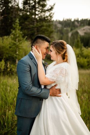Intimate wedding portraits on boardwalk surrounded by tall grass and mountain scenery.