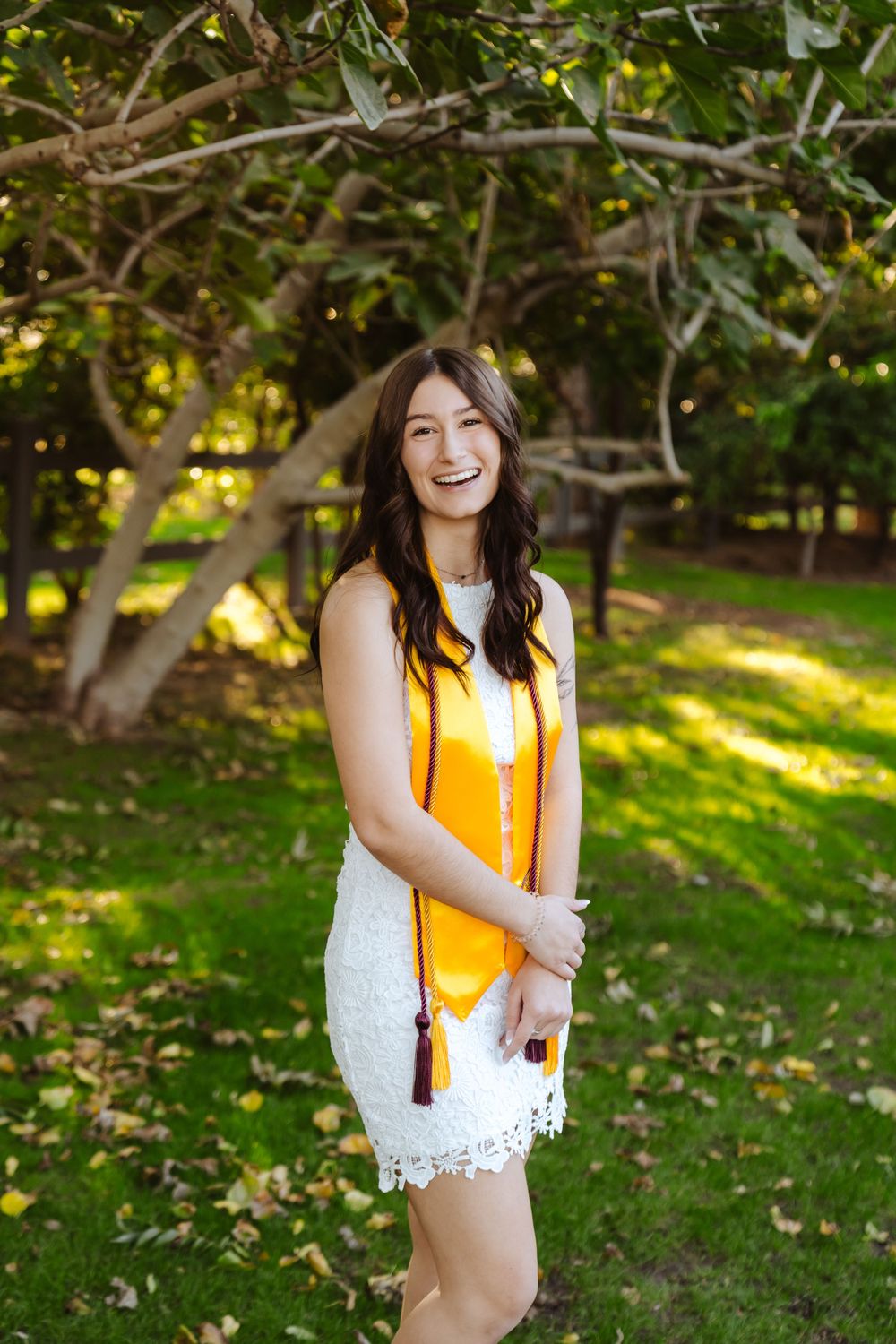 Arizona State University graduate poses under a green tree at Venue at the Grove in Phoenix