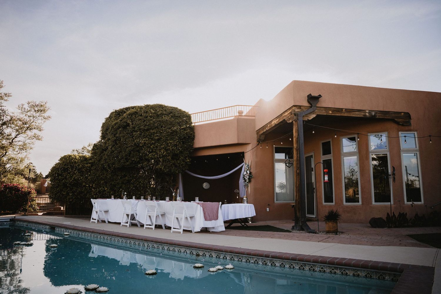 Outdoor wedding reception setup beside a pool at a adobe-style venue at dusk.cinematic destination wedding photographer