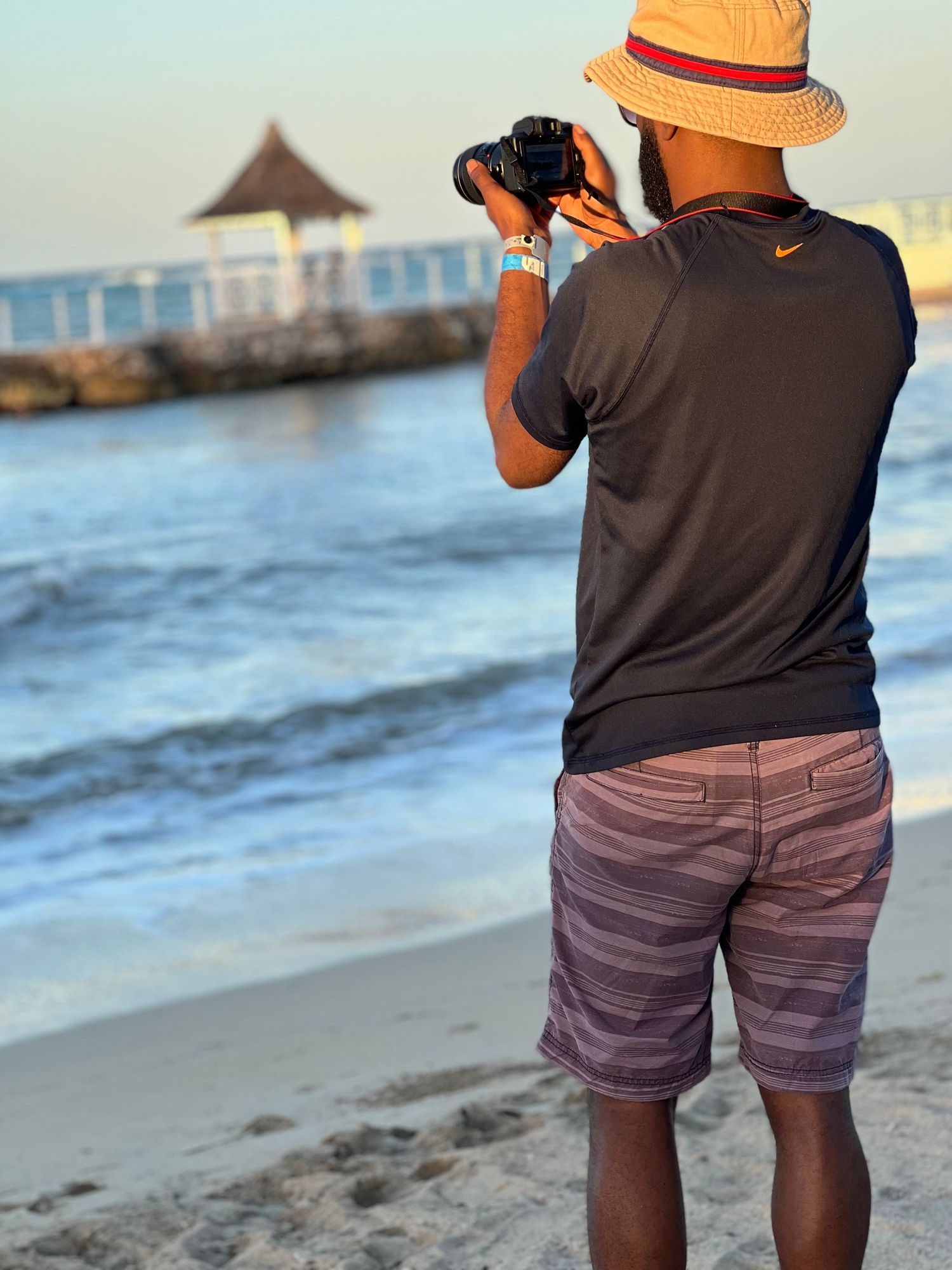 Photographer in orange hat taking pictures at the beach during sunset.