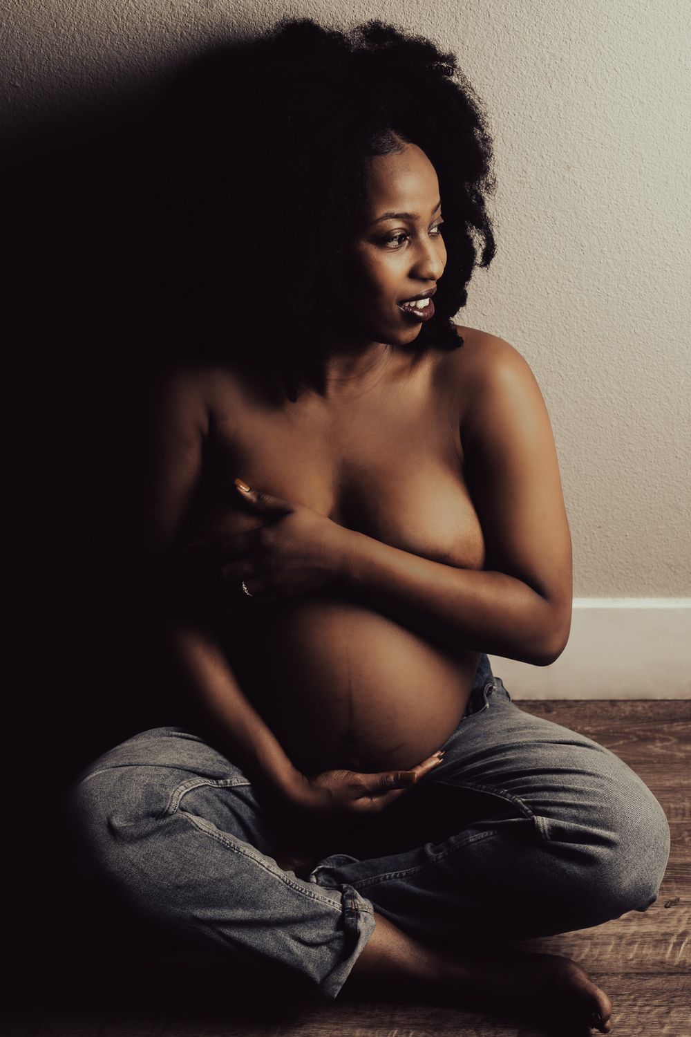 Artistic maternity portrait in dramatic lighting with natural pose.