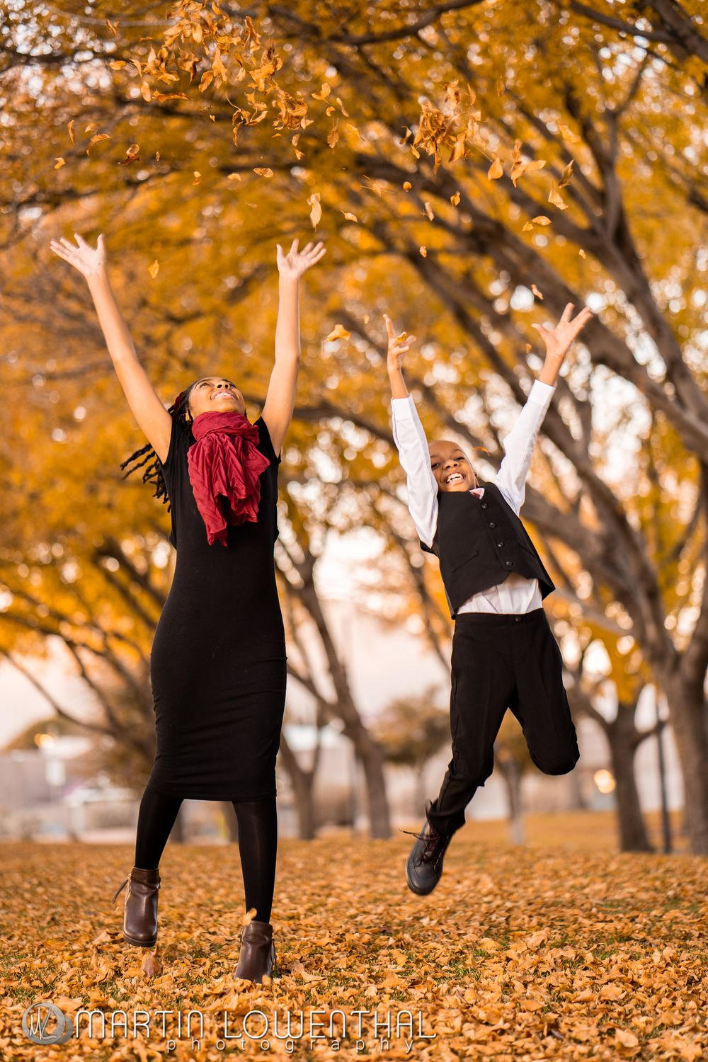 Playful autumn photoshoot showing jumping poses among fallen orange leaves.