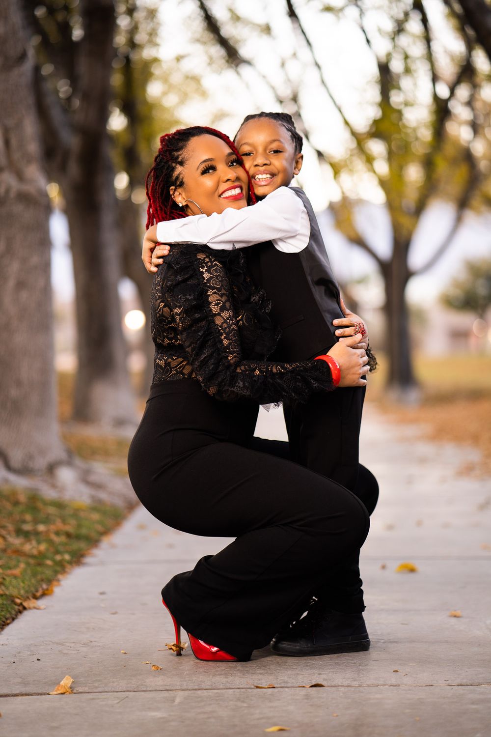Heartwarming mother and child embracing on sidewalk during autumn photo session.