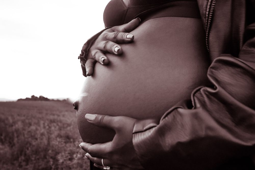 Artistic silhouette maternity portraits in sepia tones showing pregnant belly.