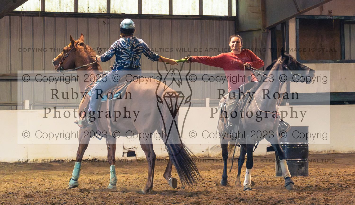 two horses and two riders passing a stick