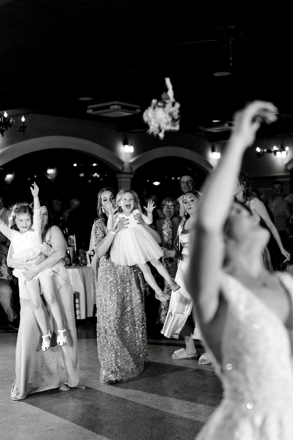 Wedding reception dance floor filled with guests celebrating in black and white photography.