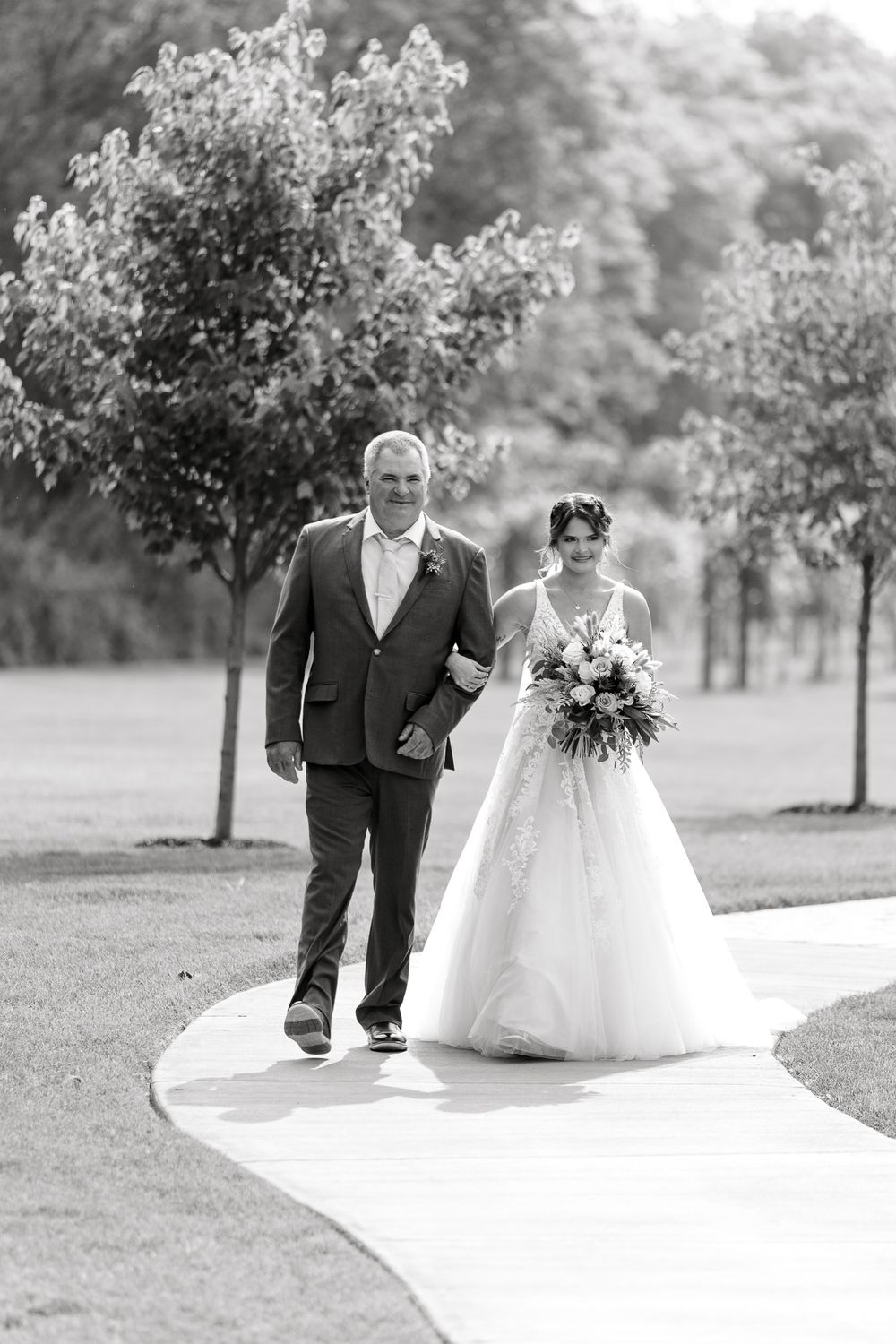 Wedding processional captured in black and white on an outdoor pathway.