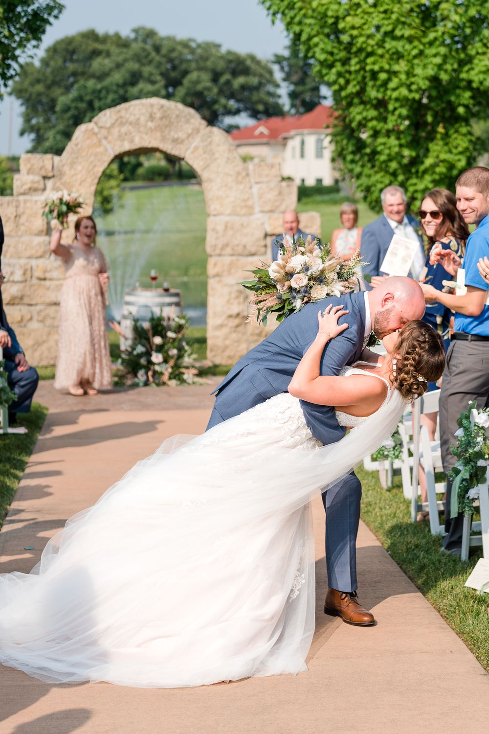 Romantic wedding moment captured at stone archway during outdoor ceremony.