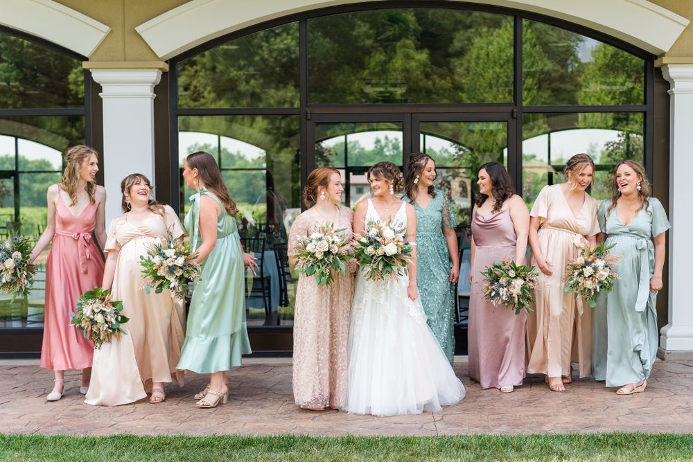 Wedding party posing under covered outdoor walkway in pastel bridesmaid dresses.