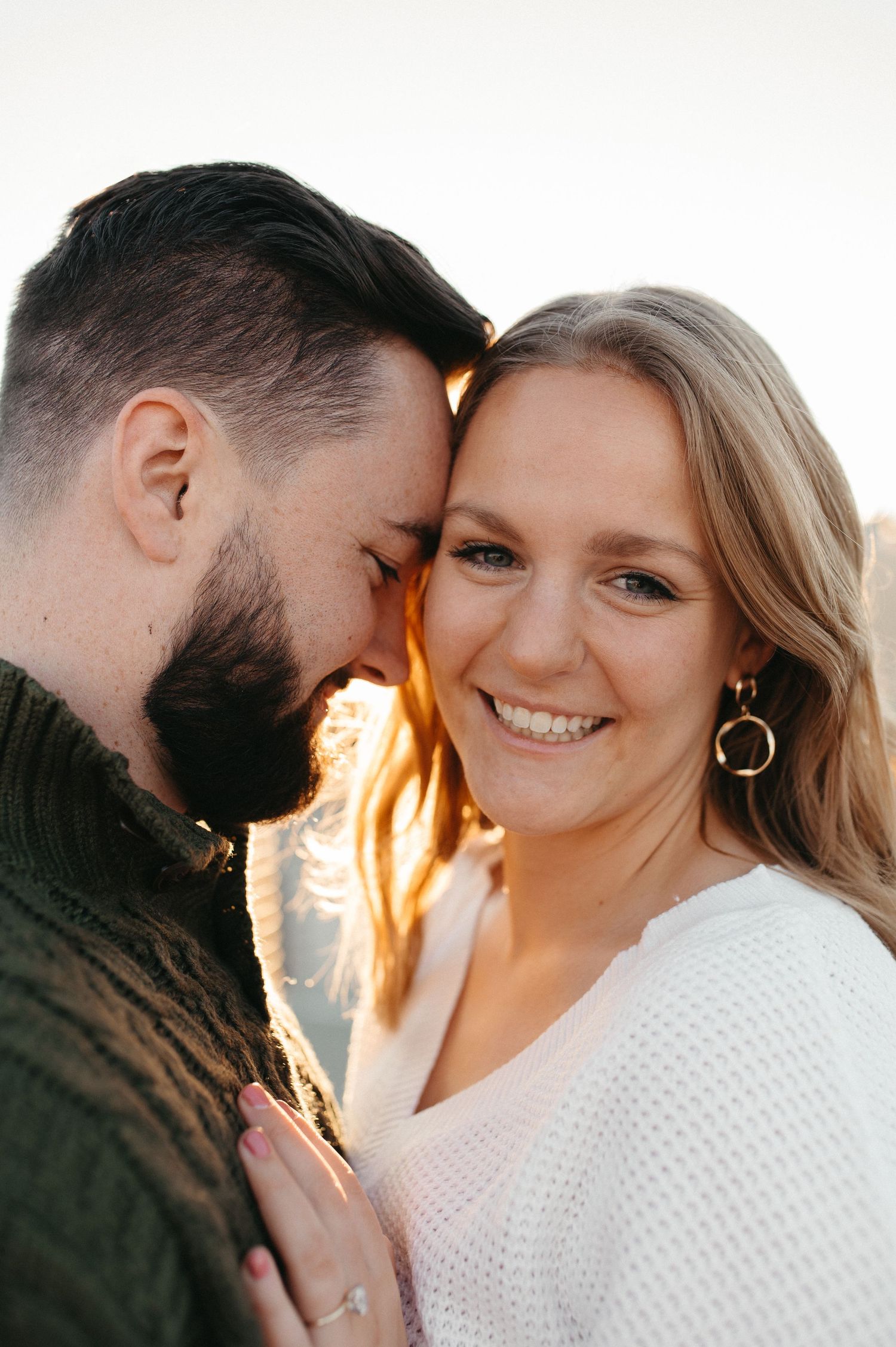 Joyful couple sharing tender moment during sunset rooftop photoshoot.
