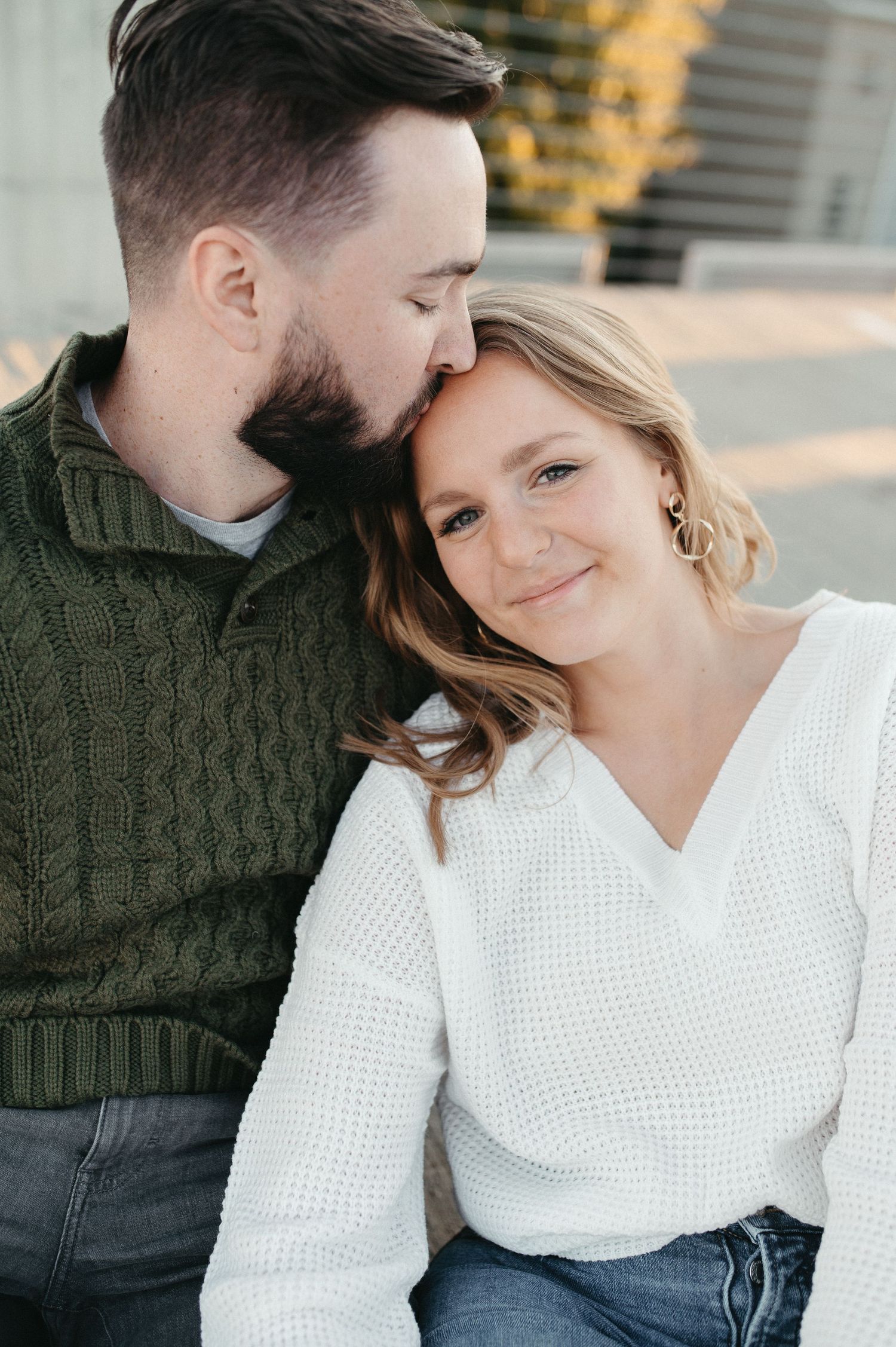 A couple in cable knit sweaters share an intimate moment while taking engagement photos.