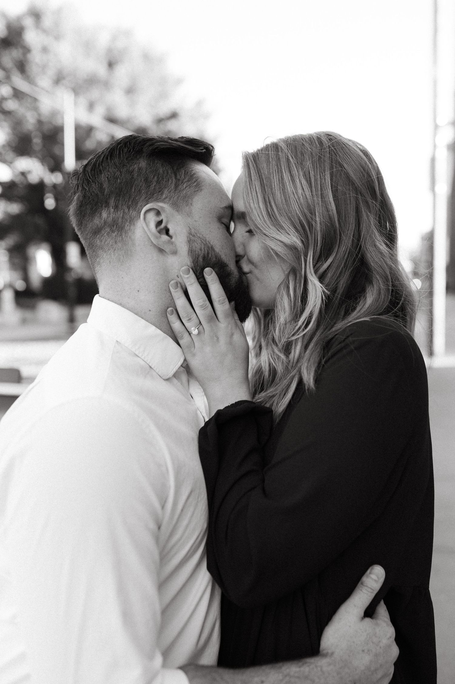 An intimate black and white portrait of a couple sharing a romantic kiss.