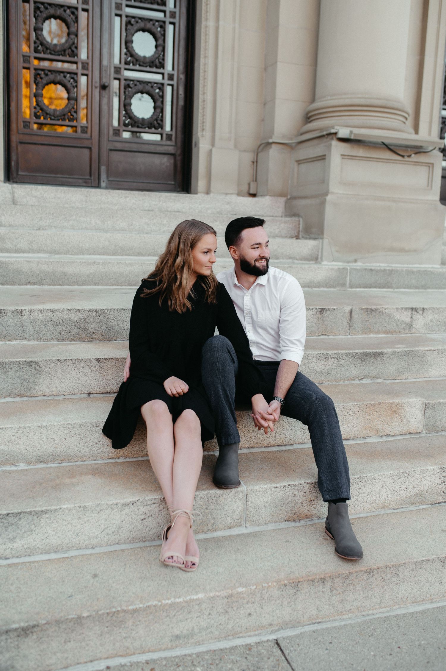 A couple shares a candid moment while sitting on stone steps during their engagement session.