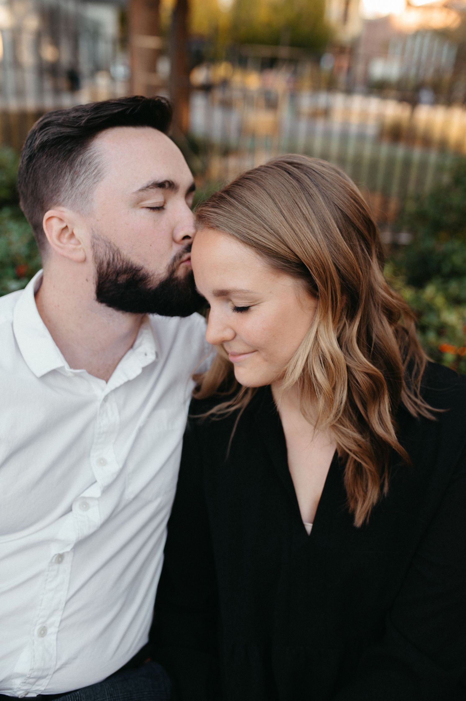 Intimate moment between couple in black and white attire against urban backdrop.