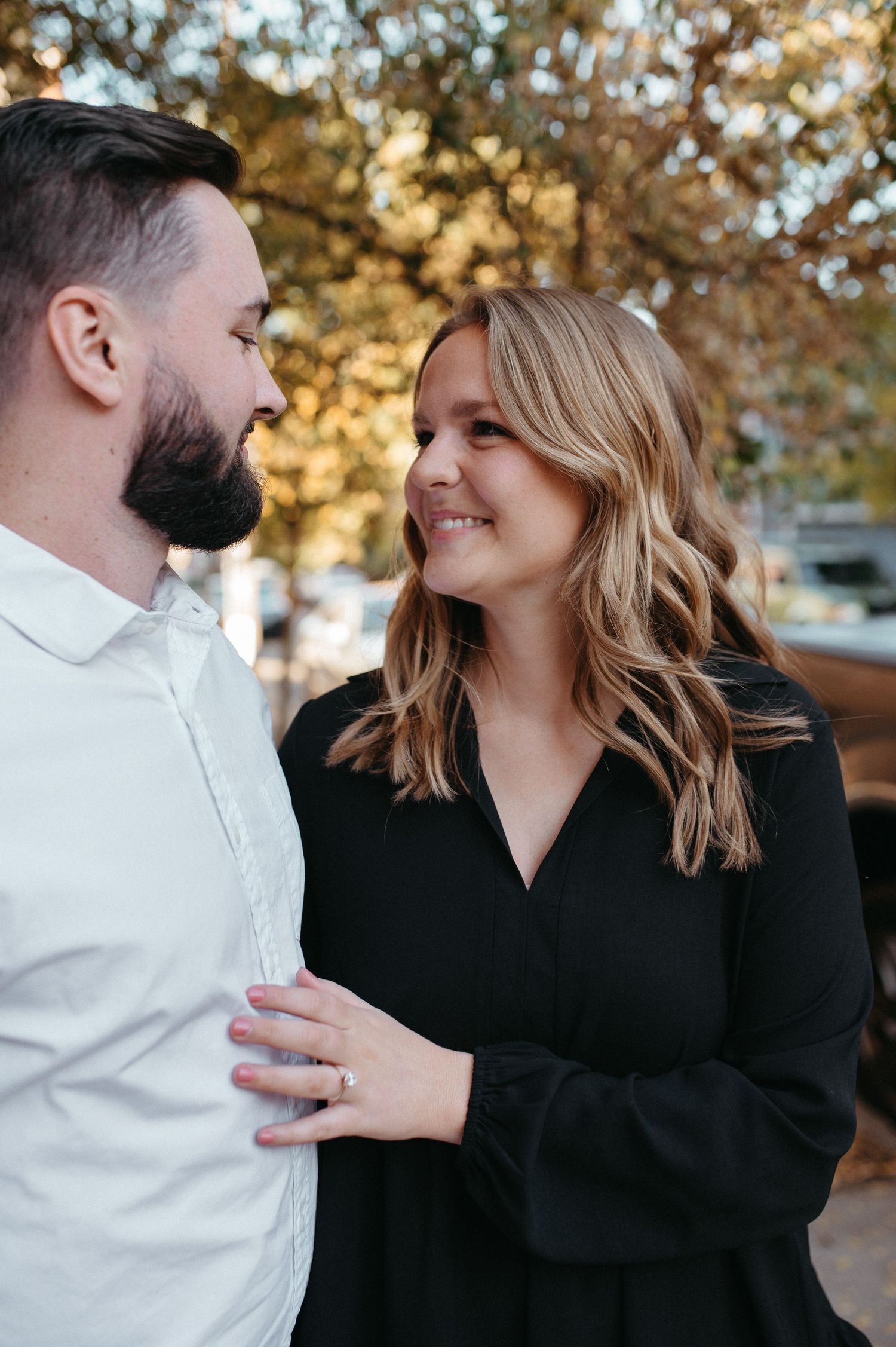A loving couple in contrasting outfits sharing a tender moment on an autumn street.