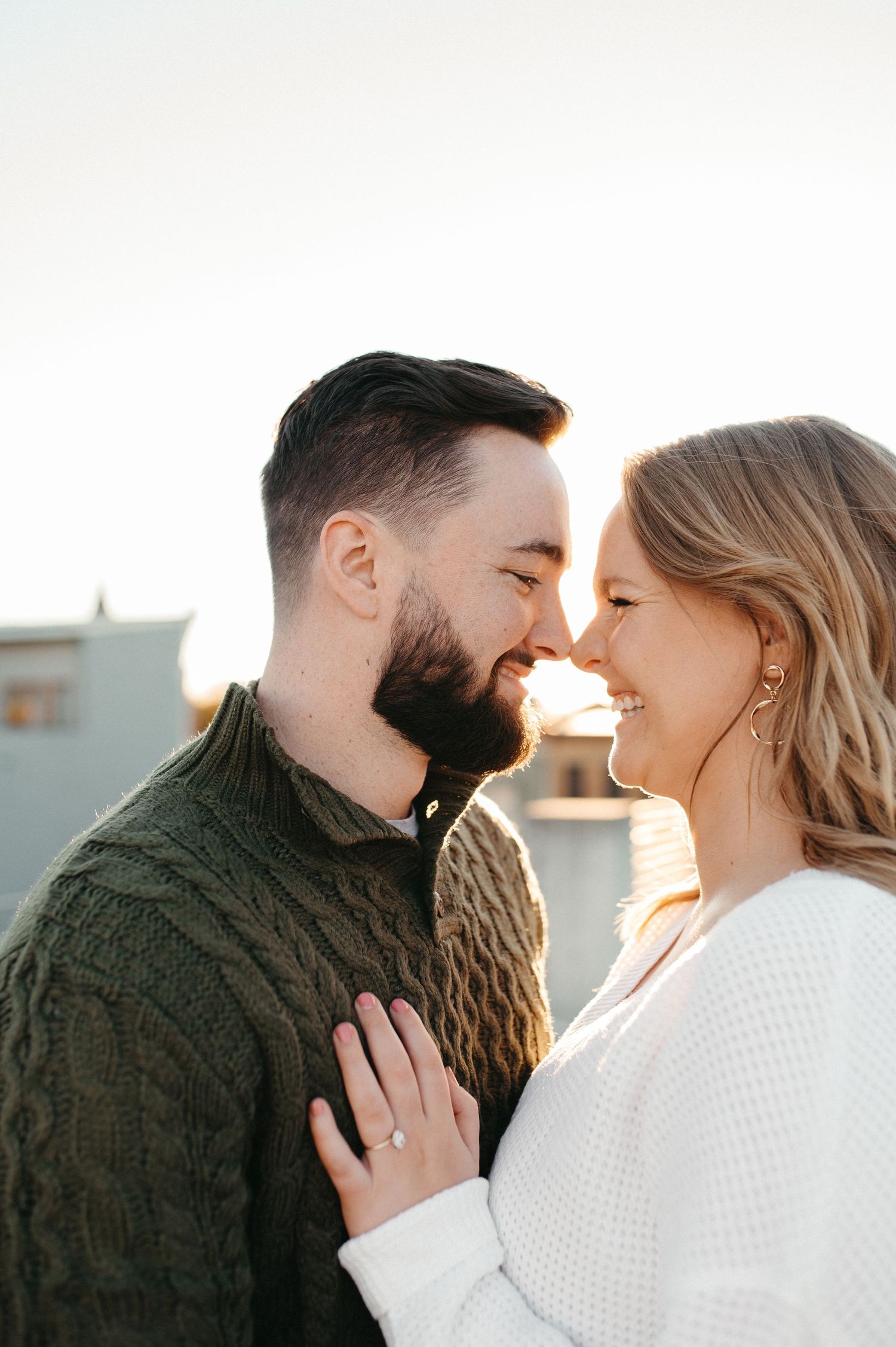 A couple sharing a romantic laugh together during their rooftop photoshoot.