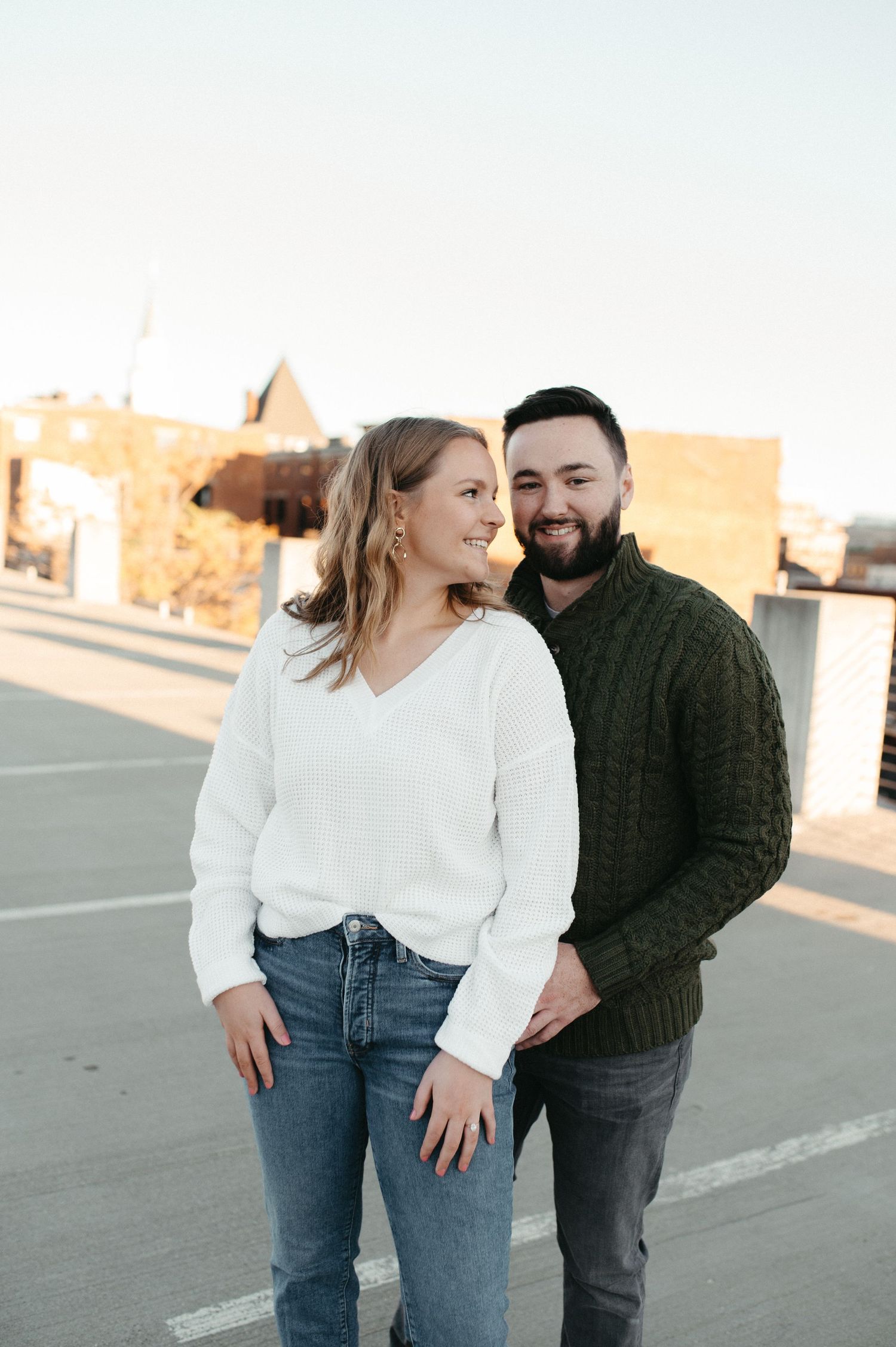 A couple in casual sweaters sharing an intimate moment on a rooftop.