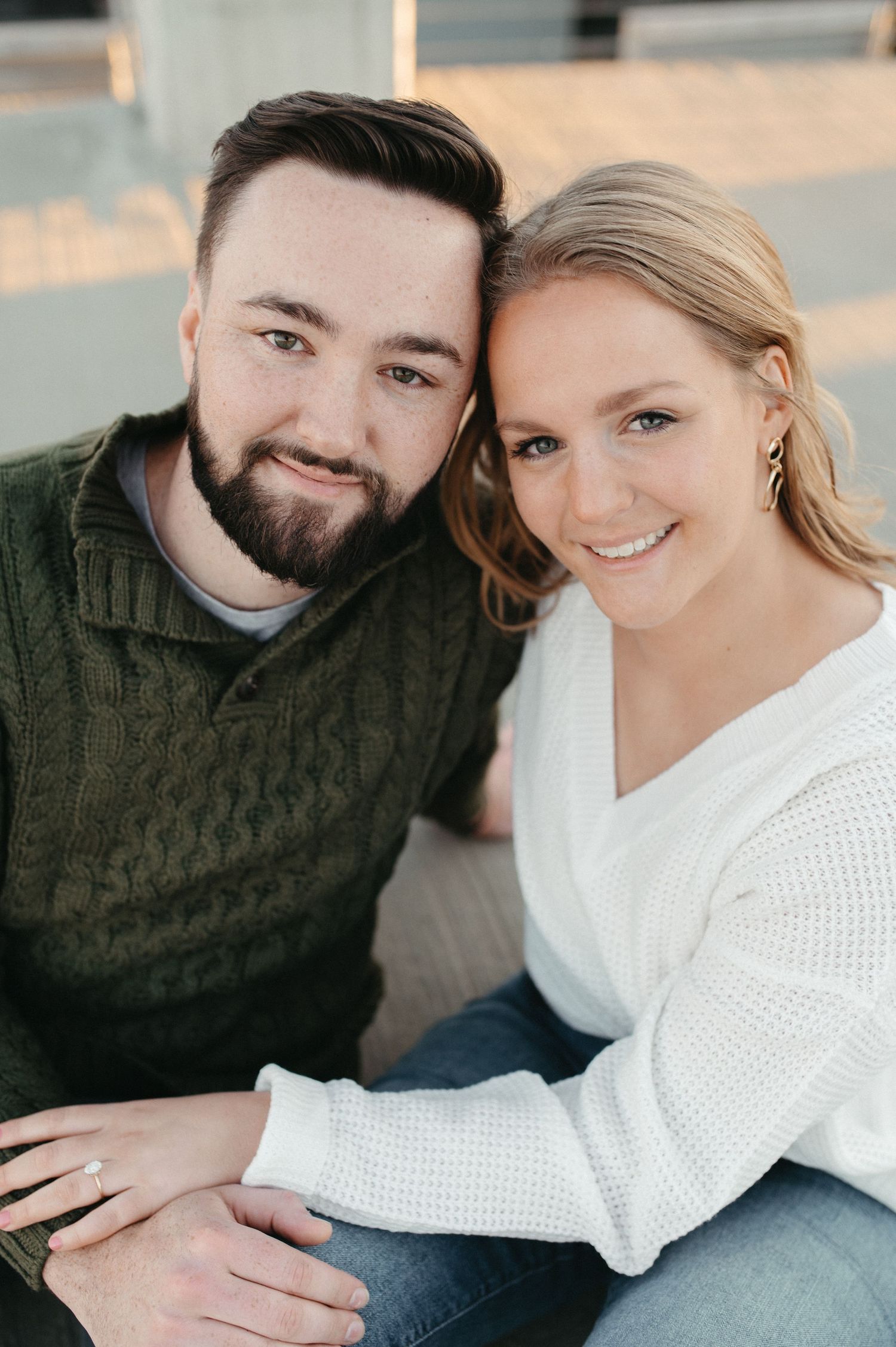 Close-up portrait of couple in casual sweaters on city rooftop.