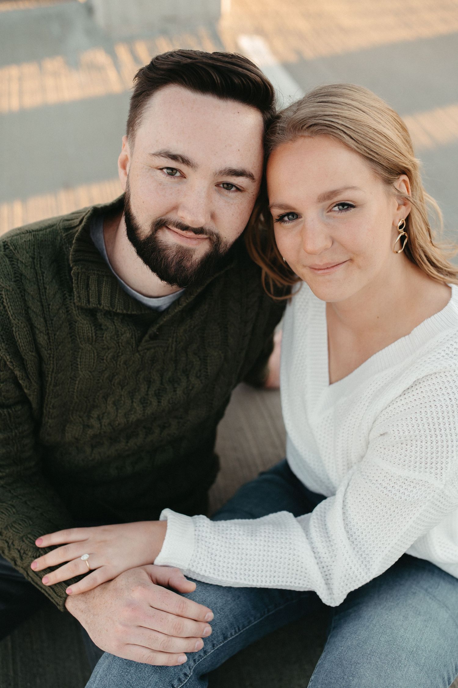 Couple smiling at camera during outdoor portrait session on urban rooftop.