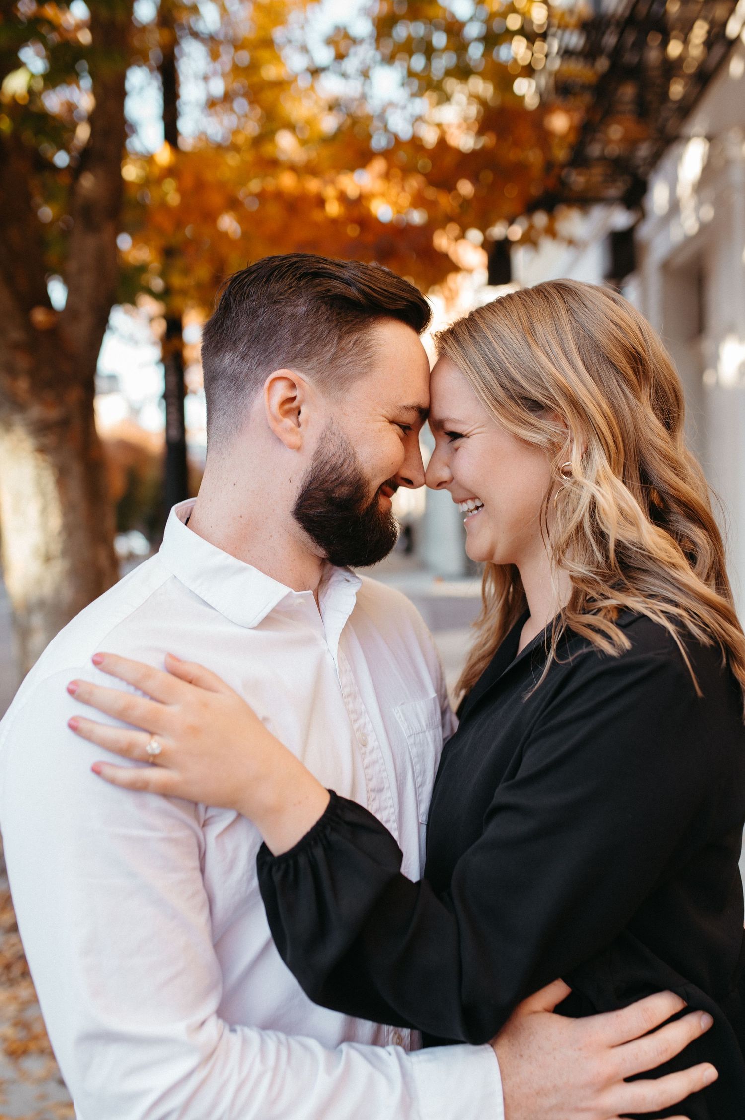 Black and white portrait of a couple touching foreheads in a tender moment.