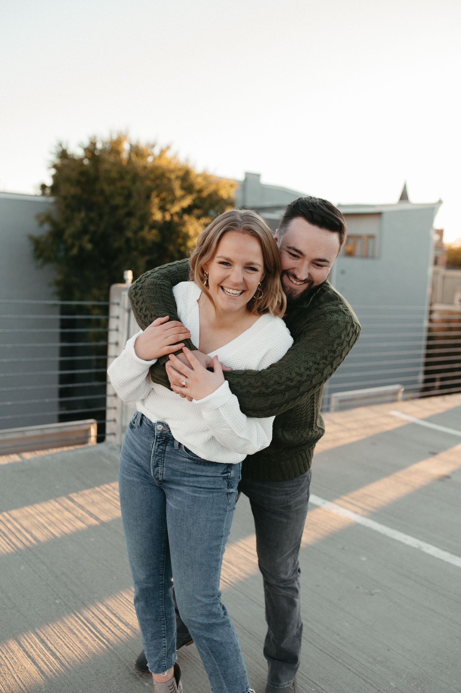 Joyful couple sharing a candid embrace on an urban rooftop during golden hour.