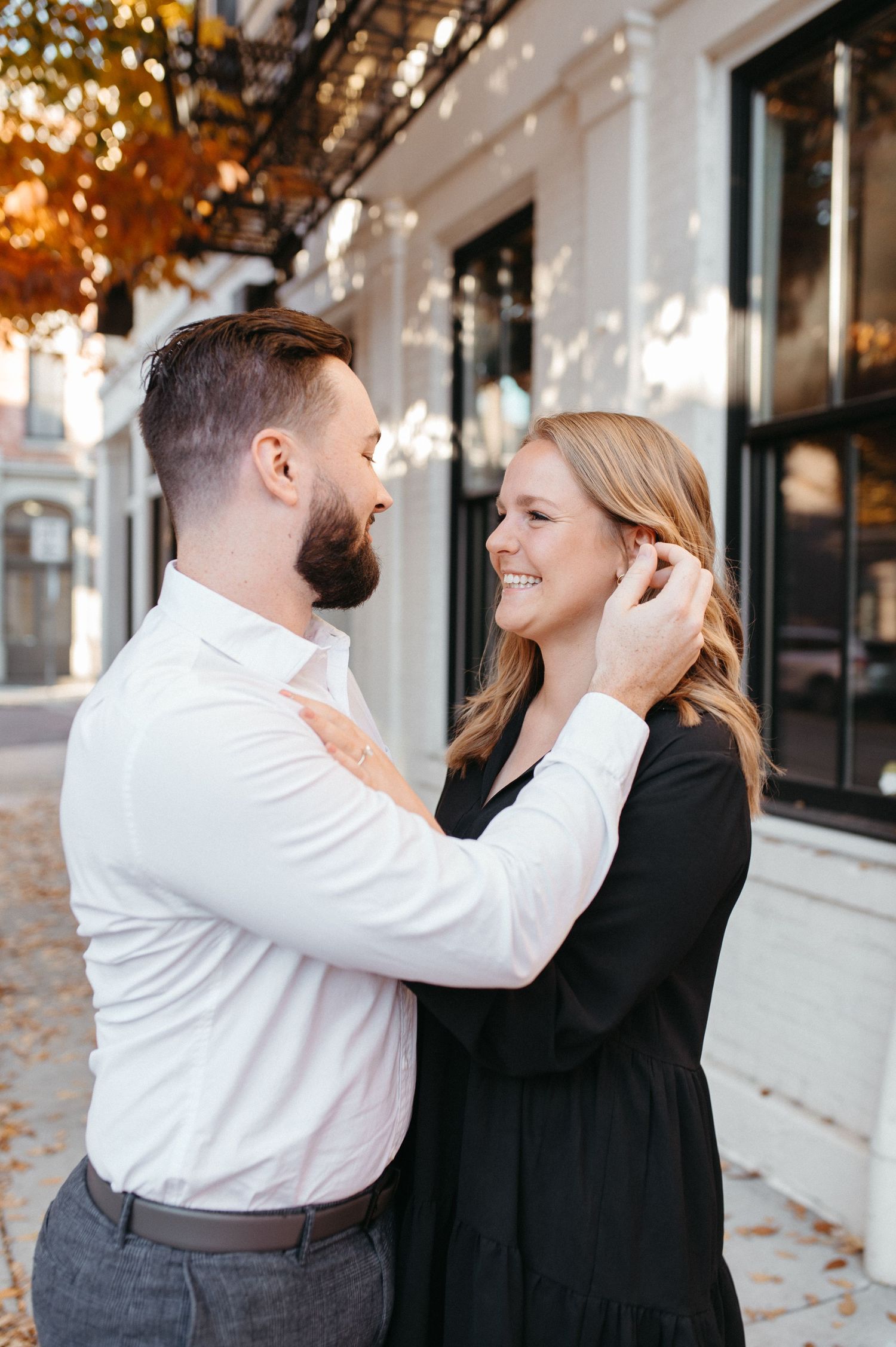 Couple embracing and laughing together on a city street during autumn.