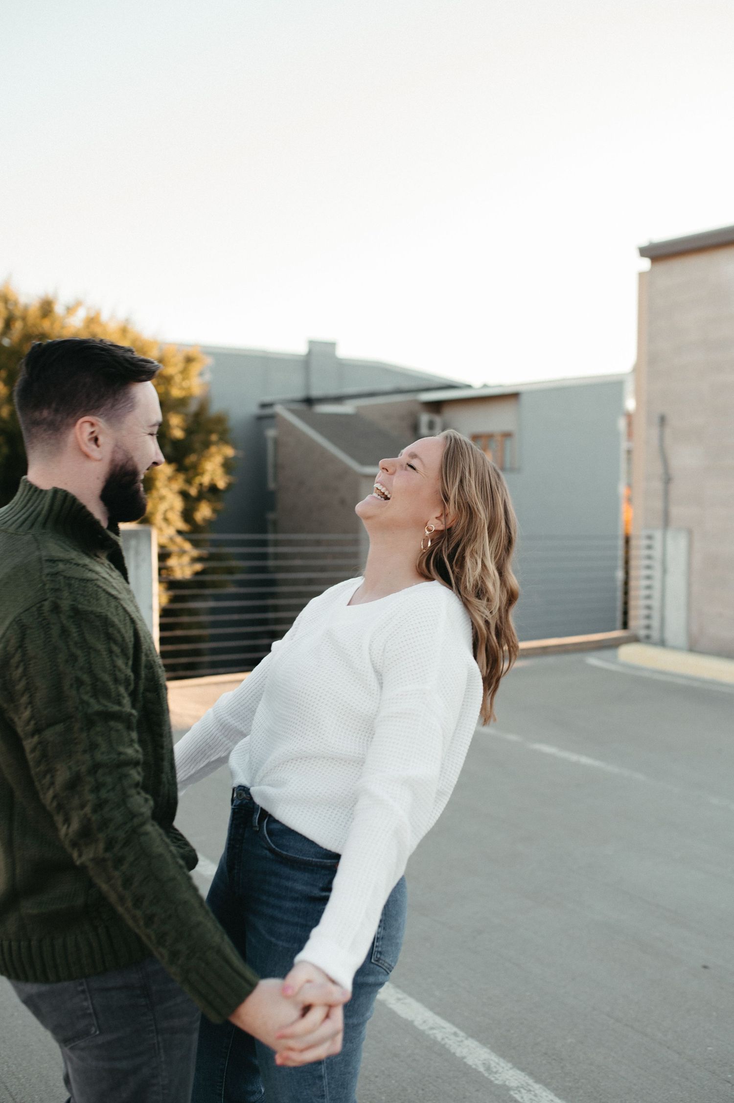 A couple sharing a lighthearted moment while dancing on a city rooftop.