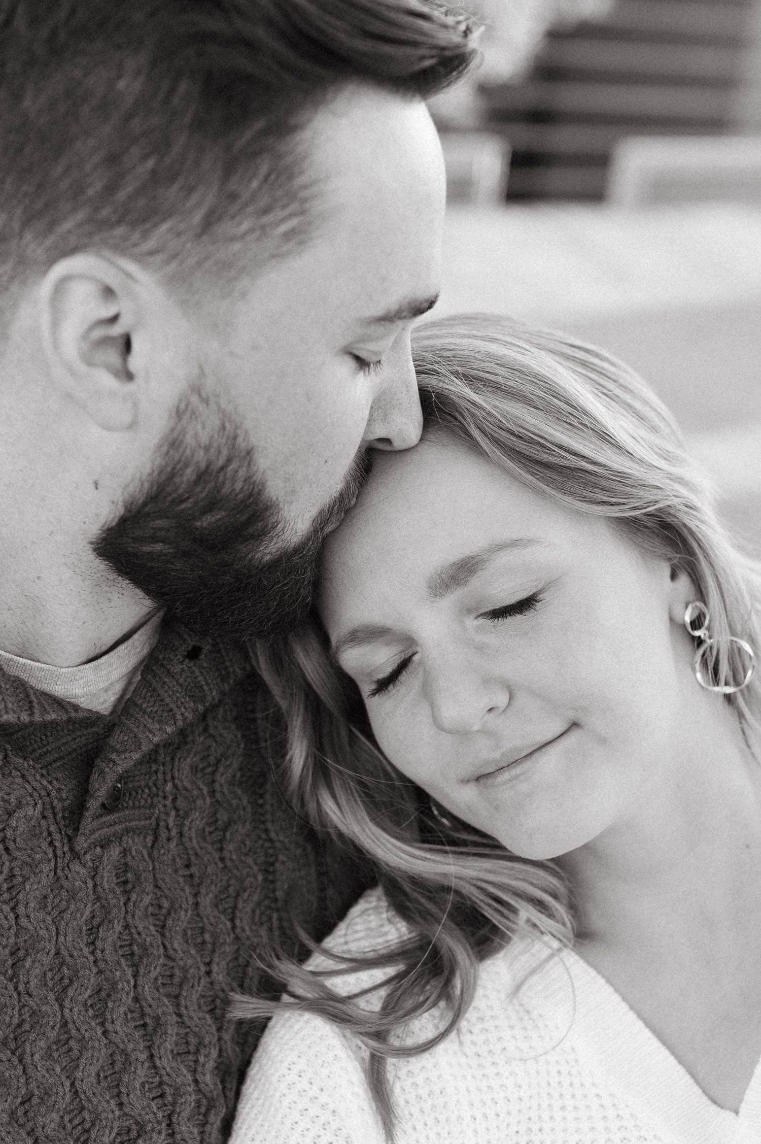 An intimate black and white portrait of a couple sharing a gentle moment together.