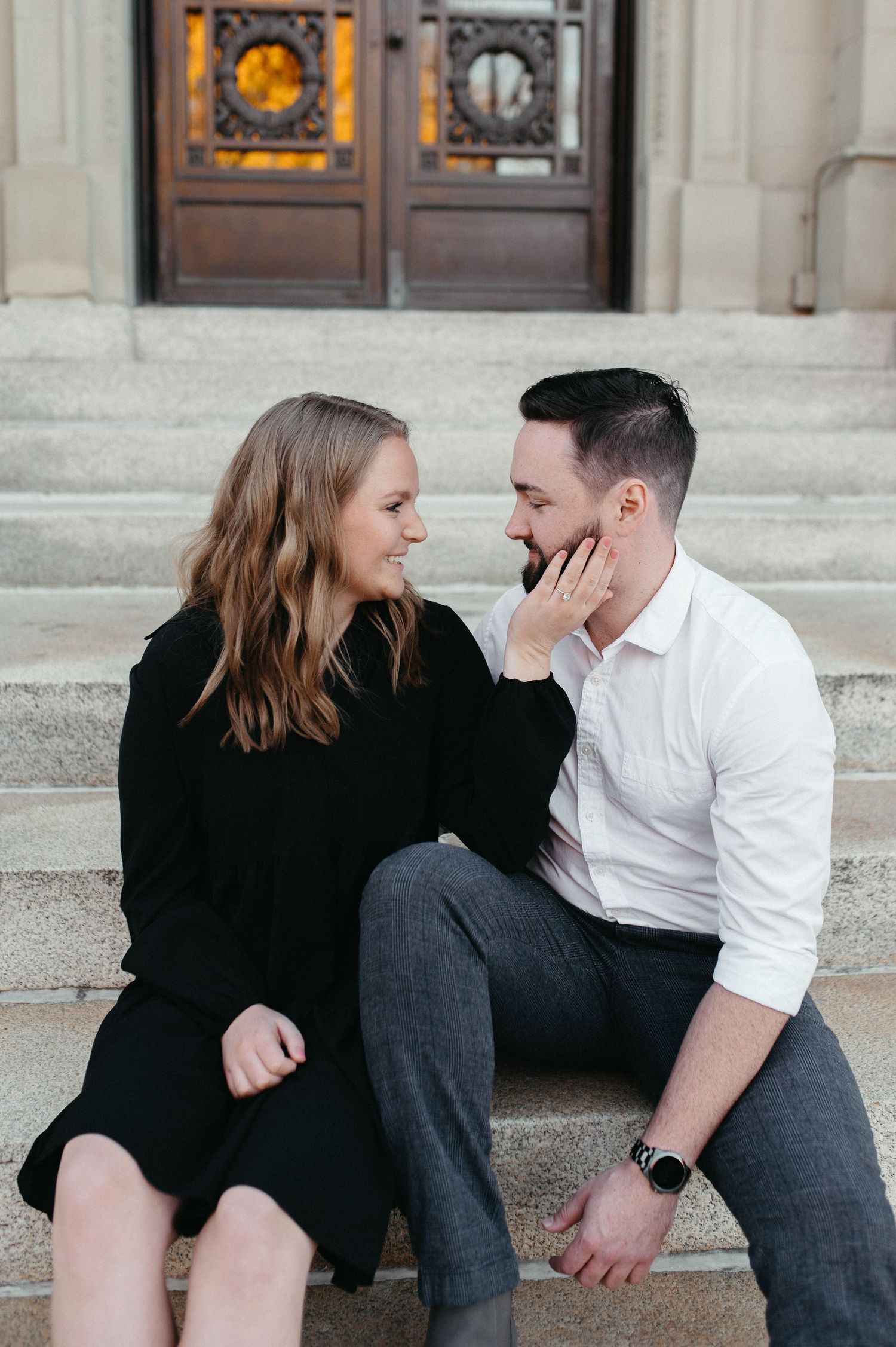 Romantic couple shares tender moment while sitting on building steps at dusk.