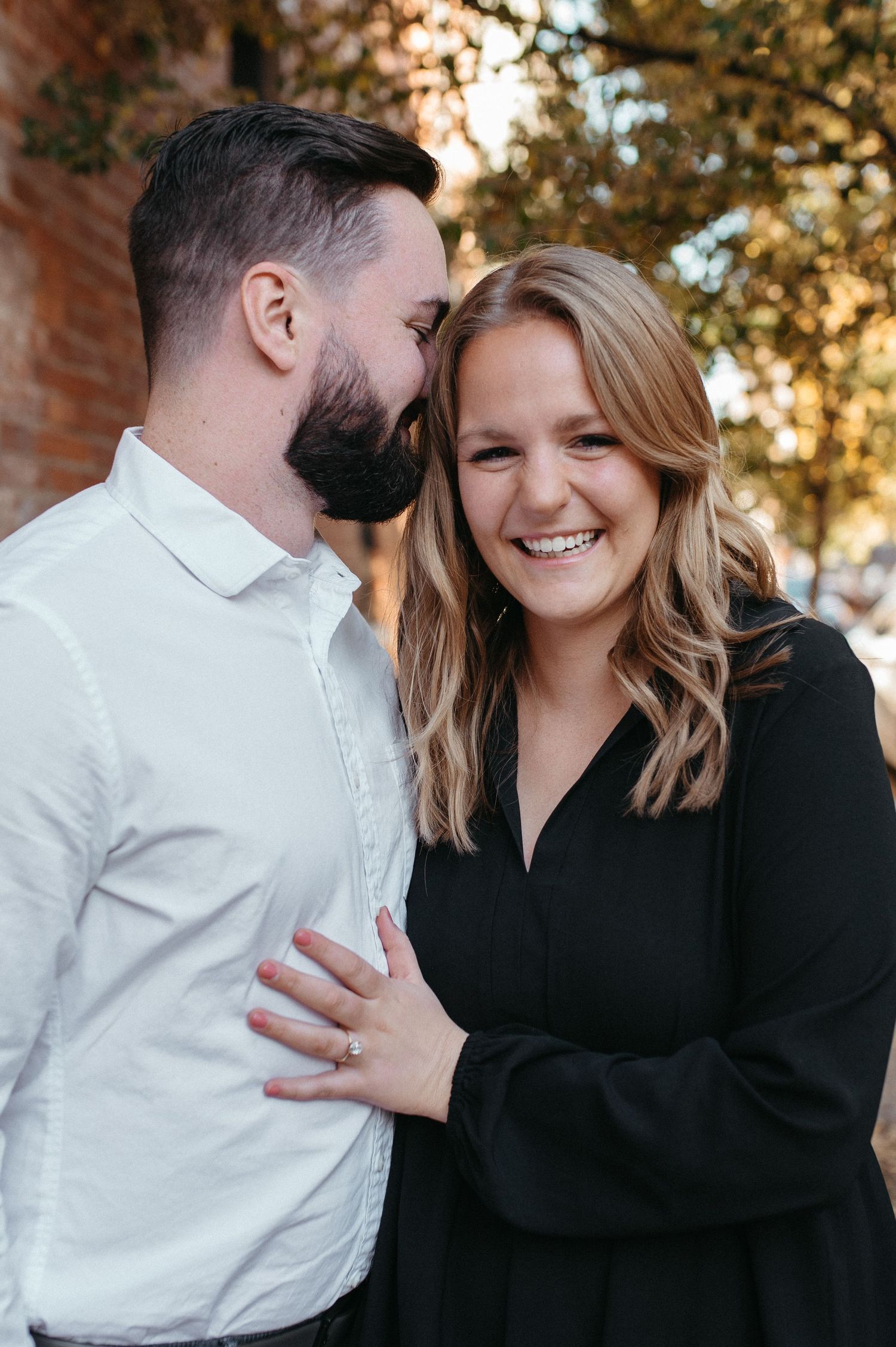 A joyful couple sharing a laugh while embracing outdoors on an autumn day.