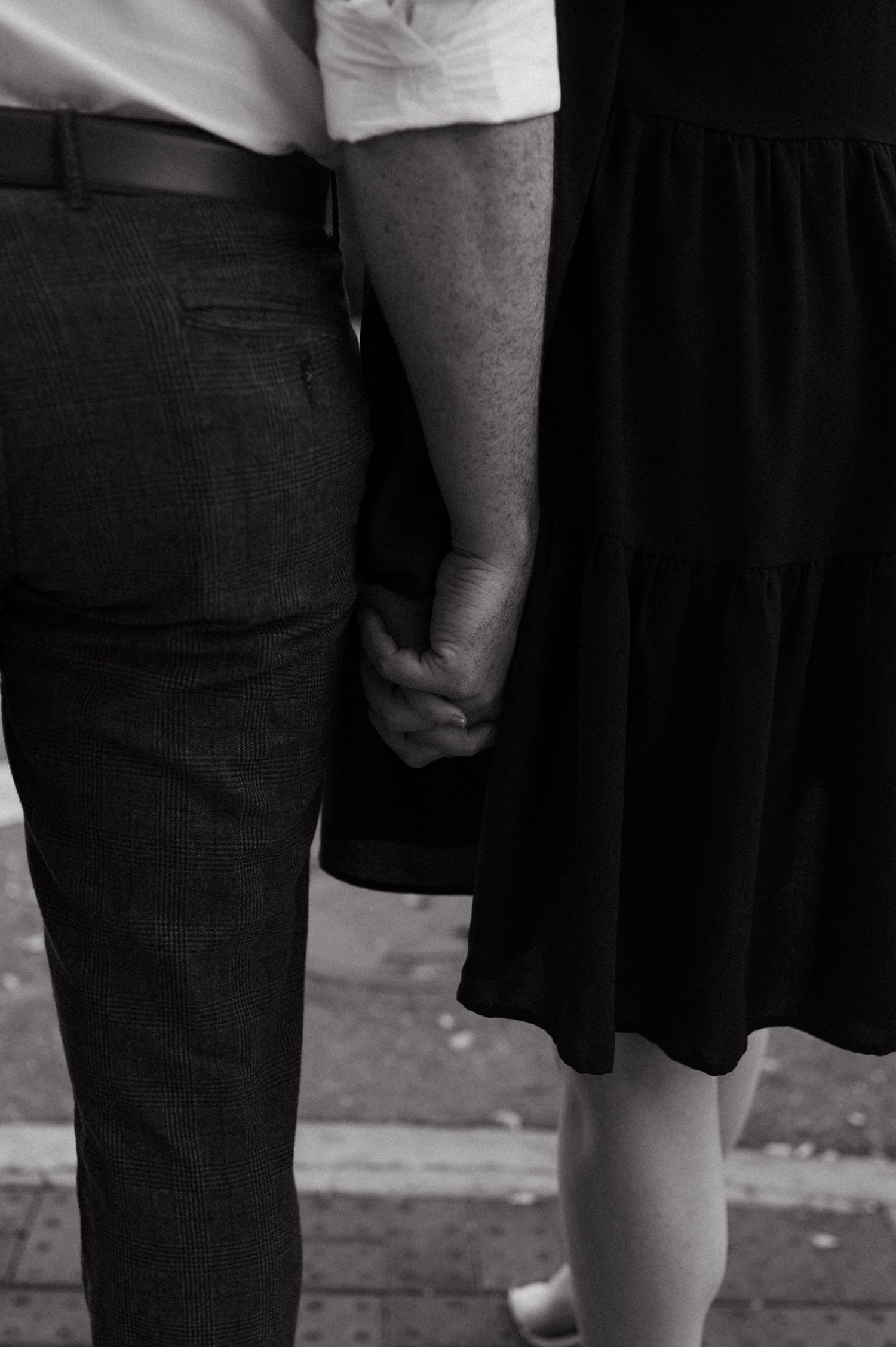 Black and white close-up of a couple holding hands while standing together.