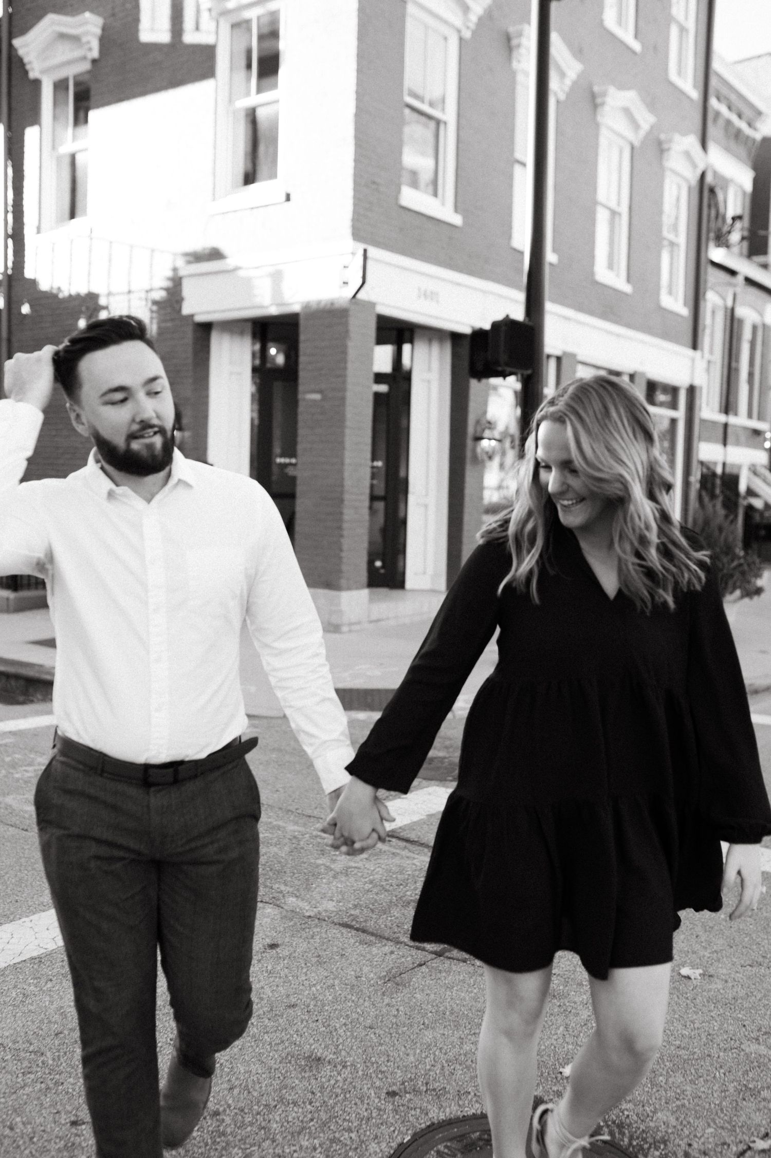 Black and white photo of a couple walking hand in hand through a city street.