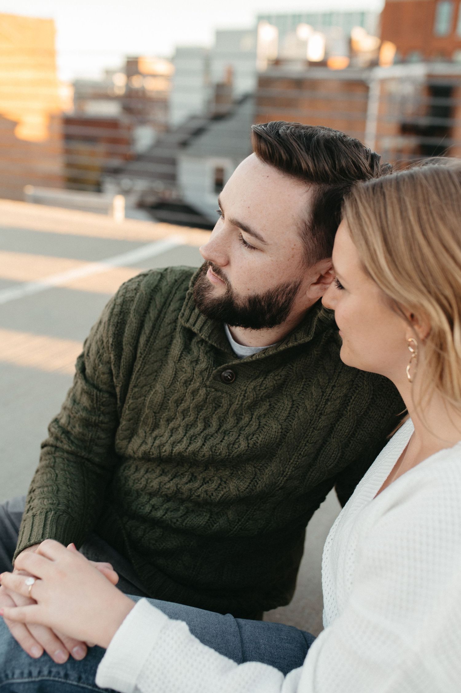 Couple sharing tender moment on rooftop with warm sunset light.