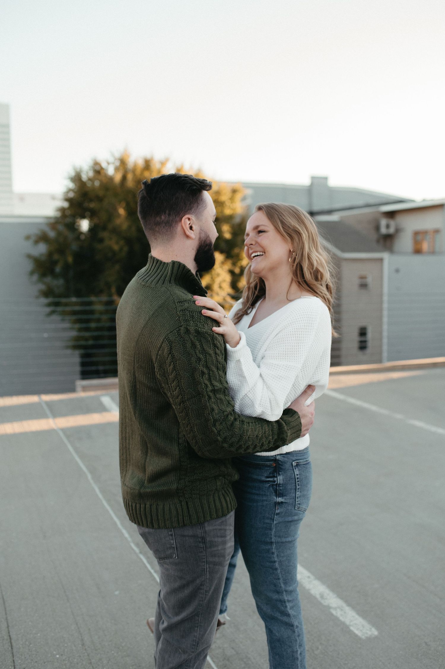 A couple shares a lighthearted moment together on a rooftop parking deck.