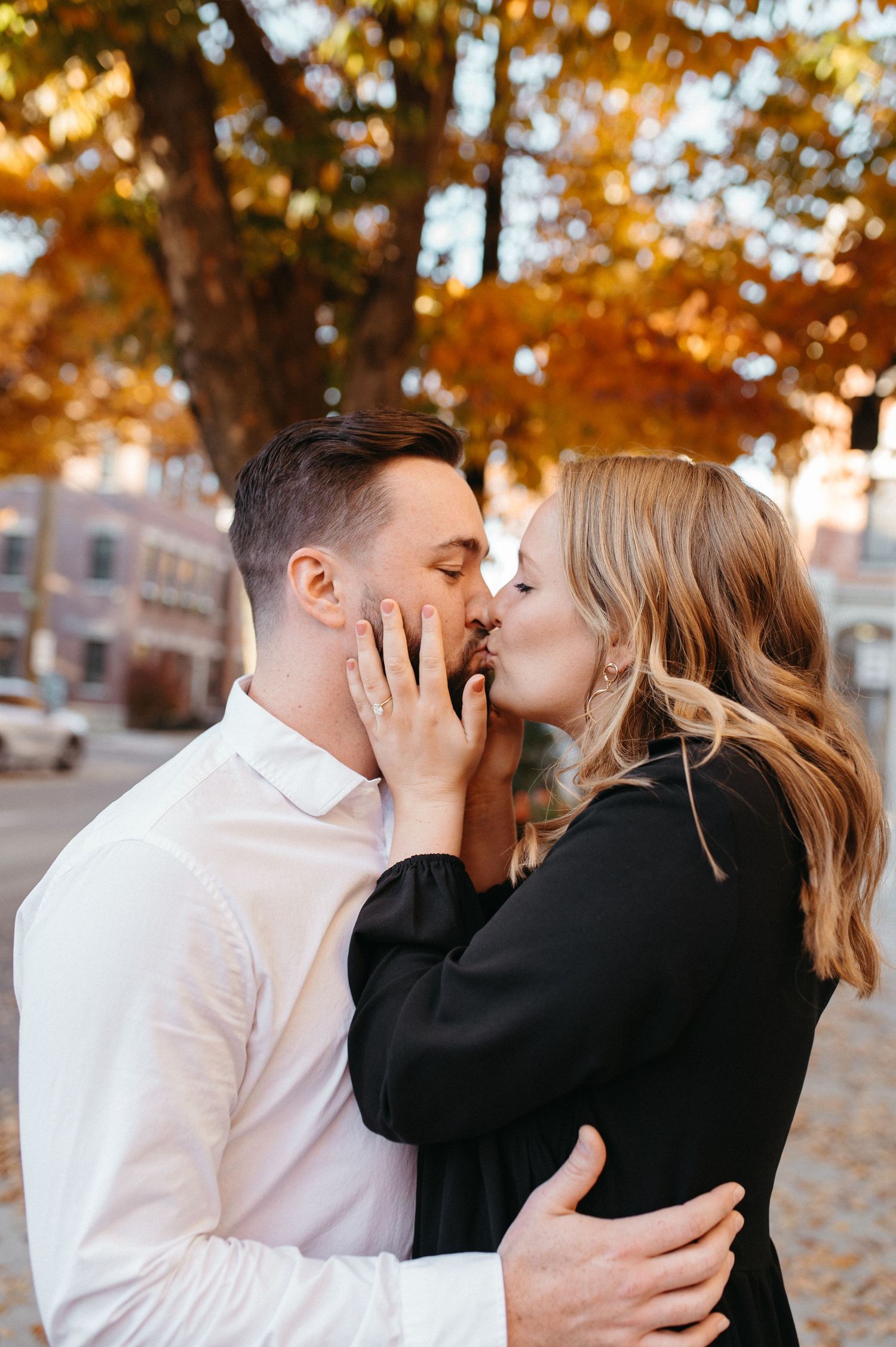 Couple in contrasting black and white outfits sharing an intimate moment on an autumn day.