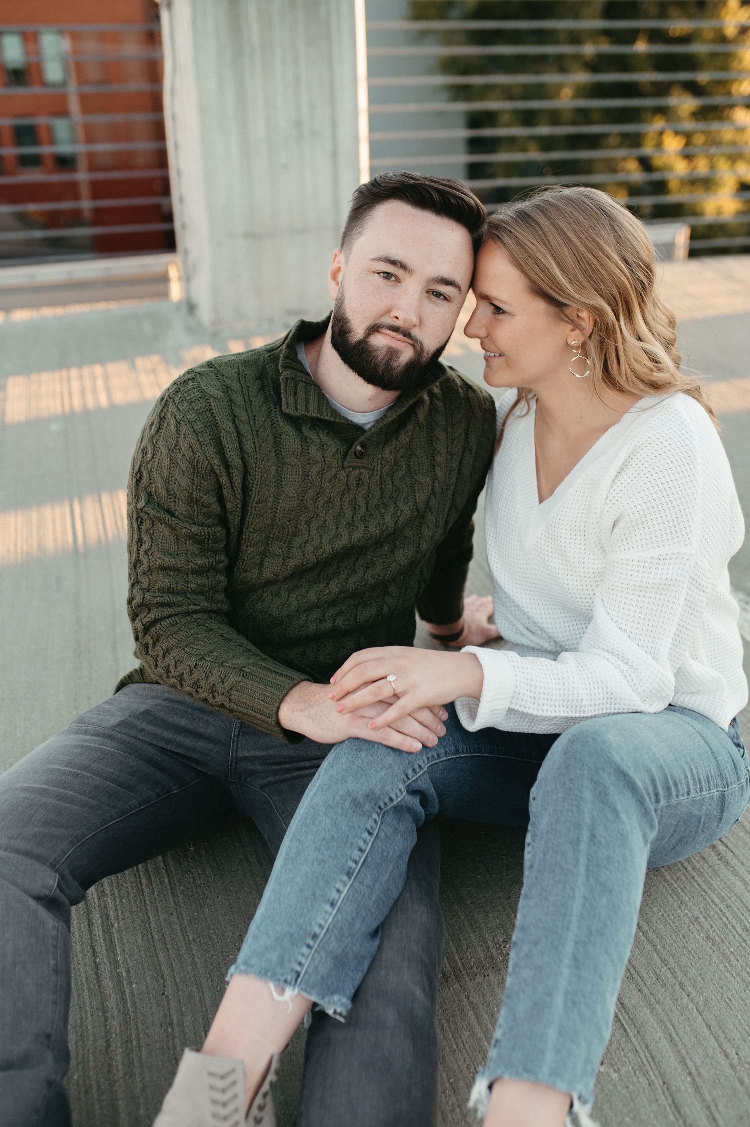 Intimate couple sitting close together on rooftop bench during sunset.