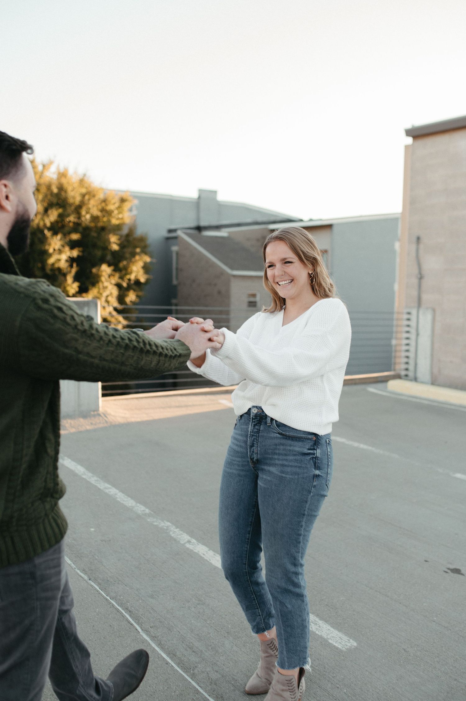 A couple holding hands and dancing playfully on an urban rooftop.