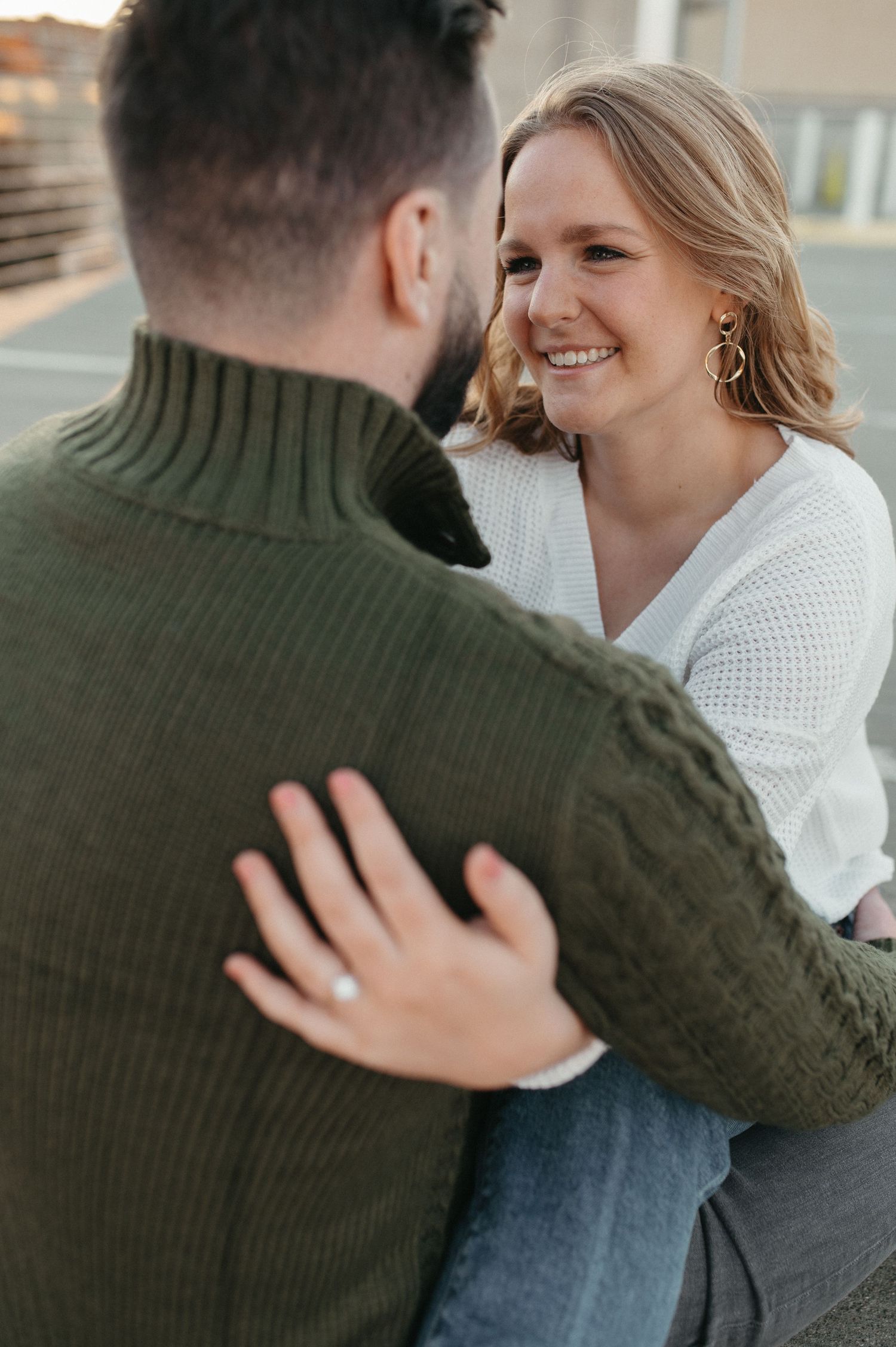 A couple in contrasting sweaters share a loving gaze during their outdoor photo session.